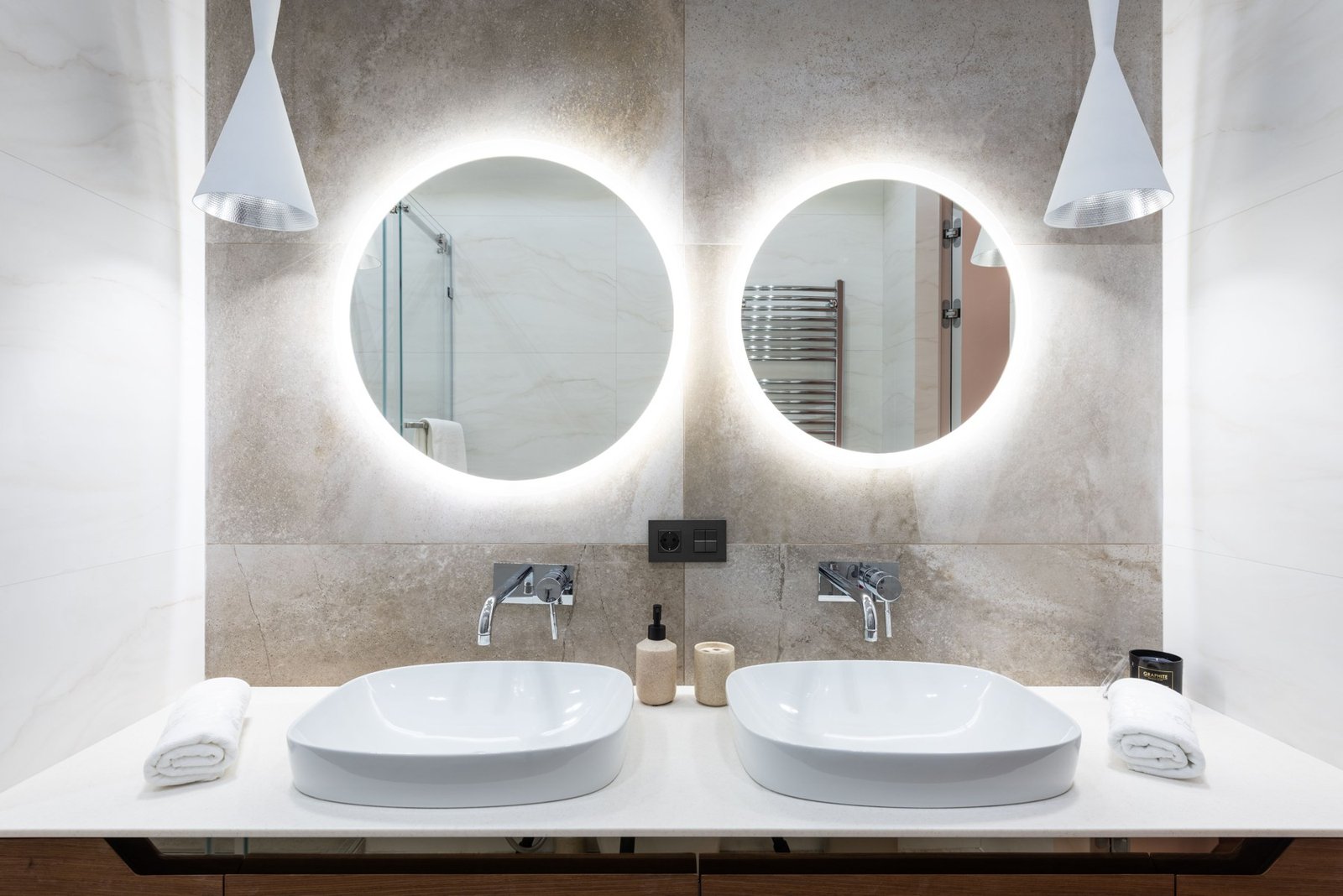 Double bathroom vanity with two round illuminated mirrors and white pendant lights
