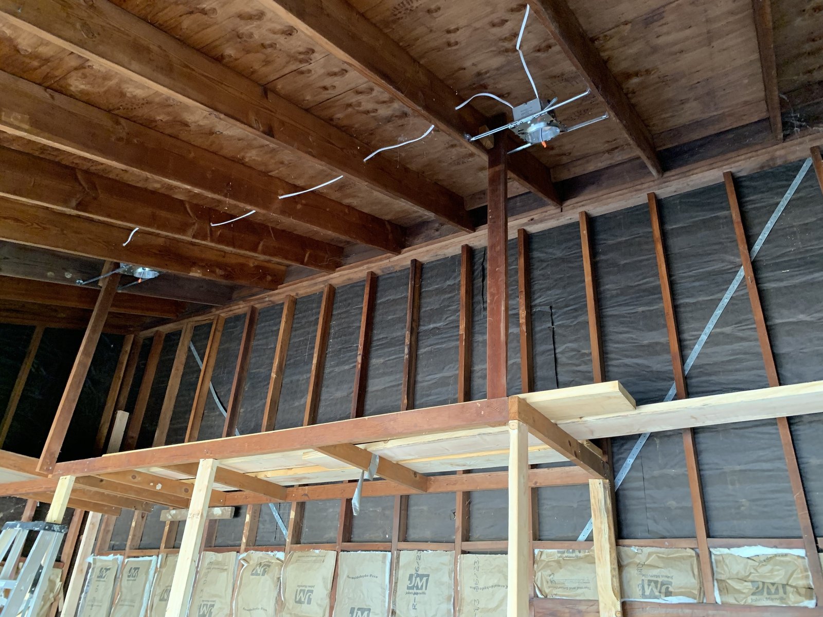 Open wood joists and wall studs with wiring, lighting rough-ins and partial insulation