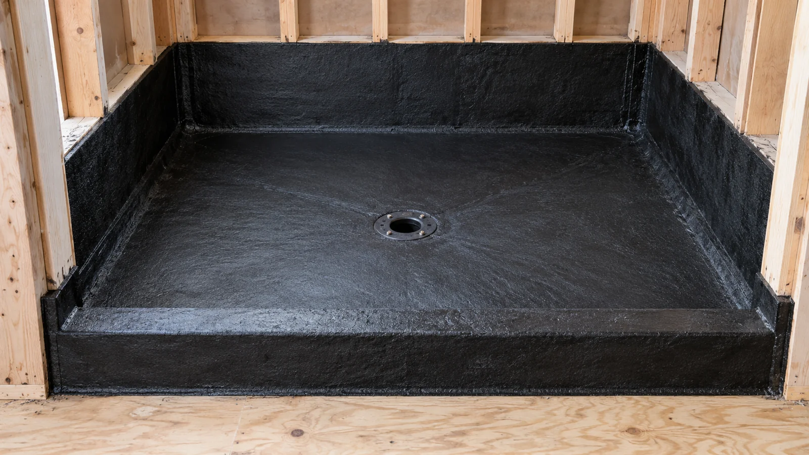 AI concept of a black hot-mop shower receptor with waterproofing upturns at three wall bases, a fully wrapped low curb and an exposed central clamping drain ring.