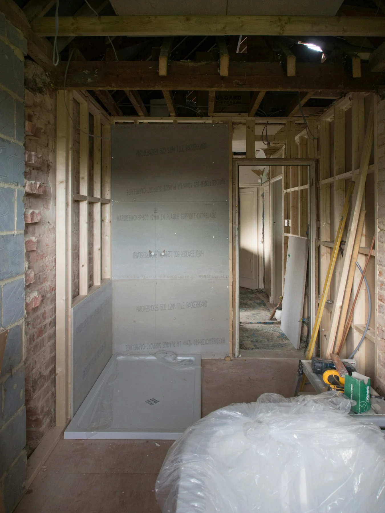 Bathroom renovation with exposed timber framing, partially installed backer board and a shower base.